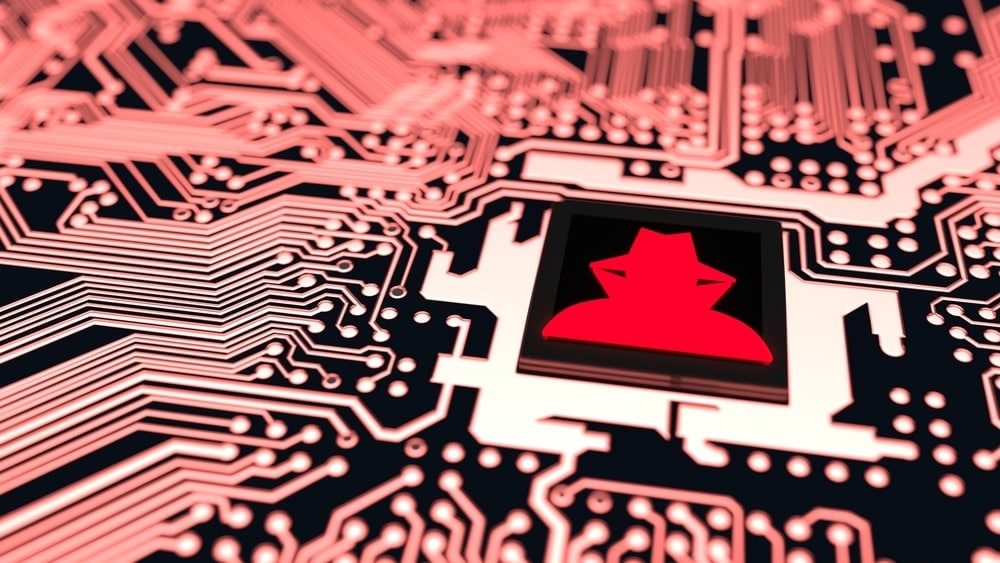 Closeup of a red-hued circuit board connected to a CPU with a red hacker symbo